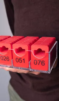 Transparente Aufbewahrungsbox gefüllt mit roten Garderobenmarken