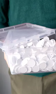 Transparente Aufbewahrungsbox gefüllt mit weißen Pfandmarken